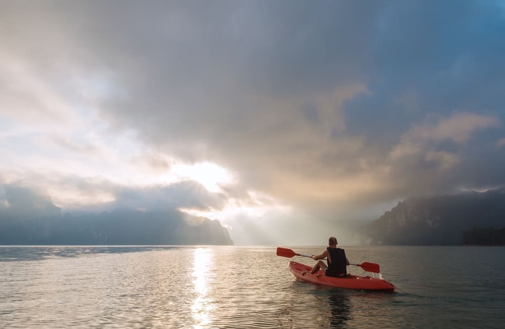 A man kayaking on a calm Cheow Lan lake