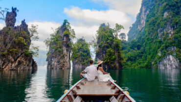 A couple on a longtail boat surrounded by limestone cliffs in Khao Sok National Park