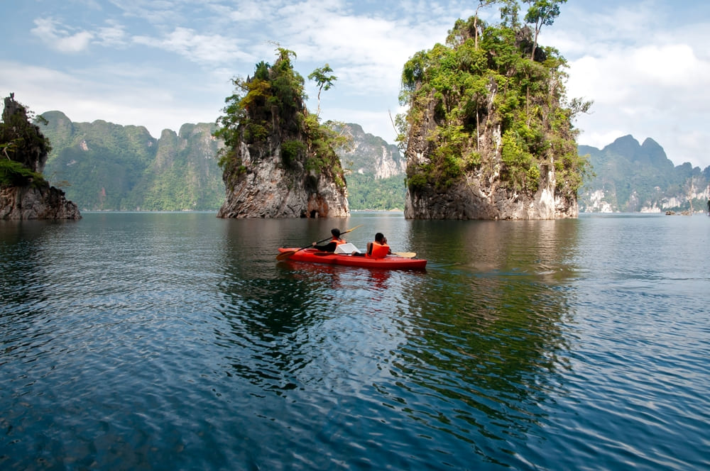 A group kayaking on Cheow Lan Lake surrounded by karst cliffs on a Khao Sok group trip