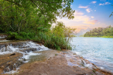 Small cascade flowing into Cheow Lan Lake at sunset, a scenic waterfall in Khao Sok to explore