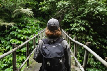 Beginner trekker walking along a jungle trail through green foliage while trekking in Khao Sok.